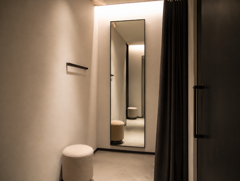 Soft warm lighting inside a store fitting room with a mirror and diffused overhead light