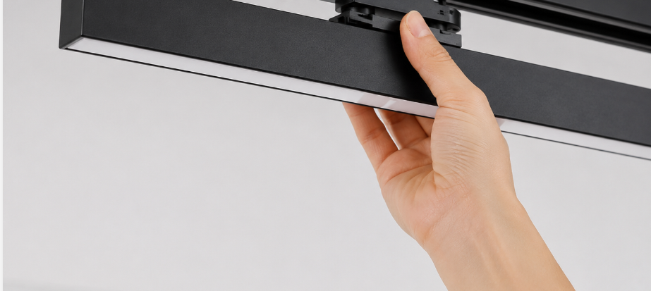 Diagram-style photo of a track linear light being clipped onto a ceiling busbar rail during installation