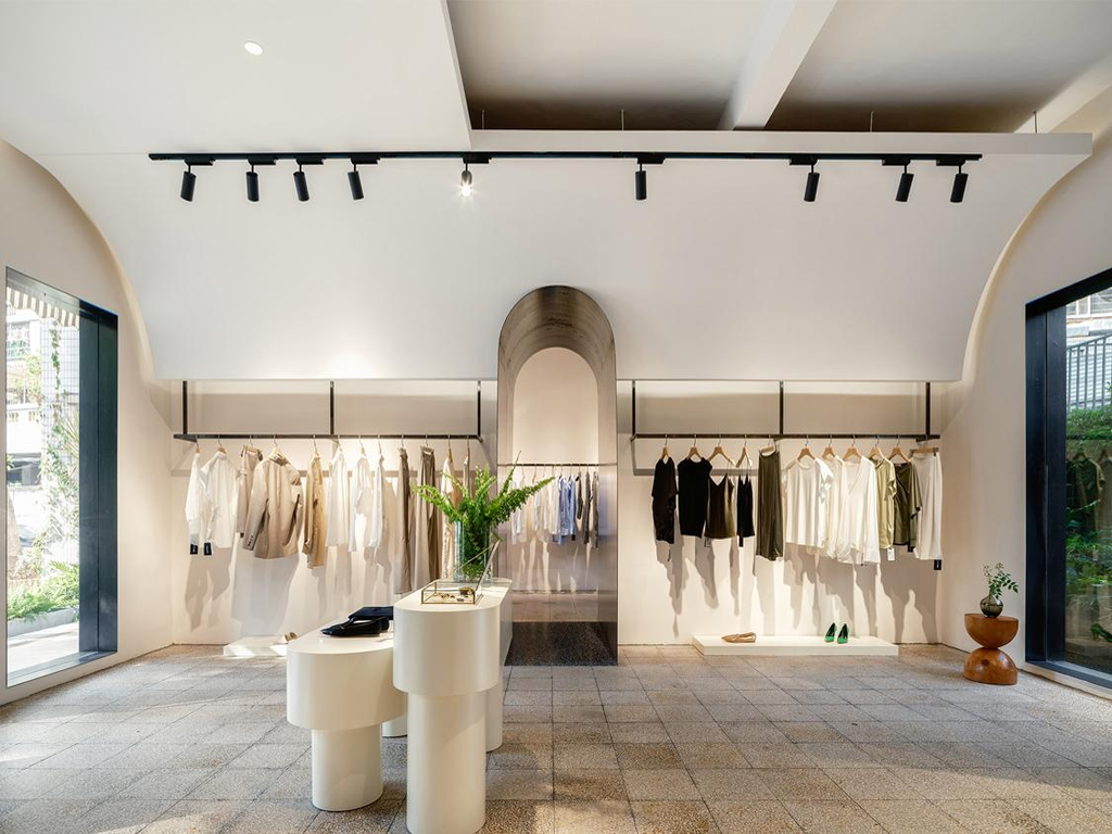 Black LED track lights illuminating clothing displays in a modern European fashion boutique